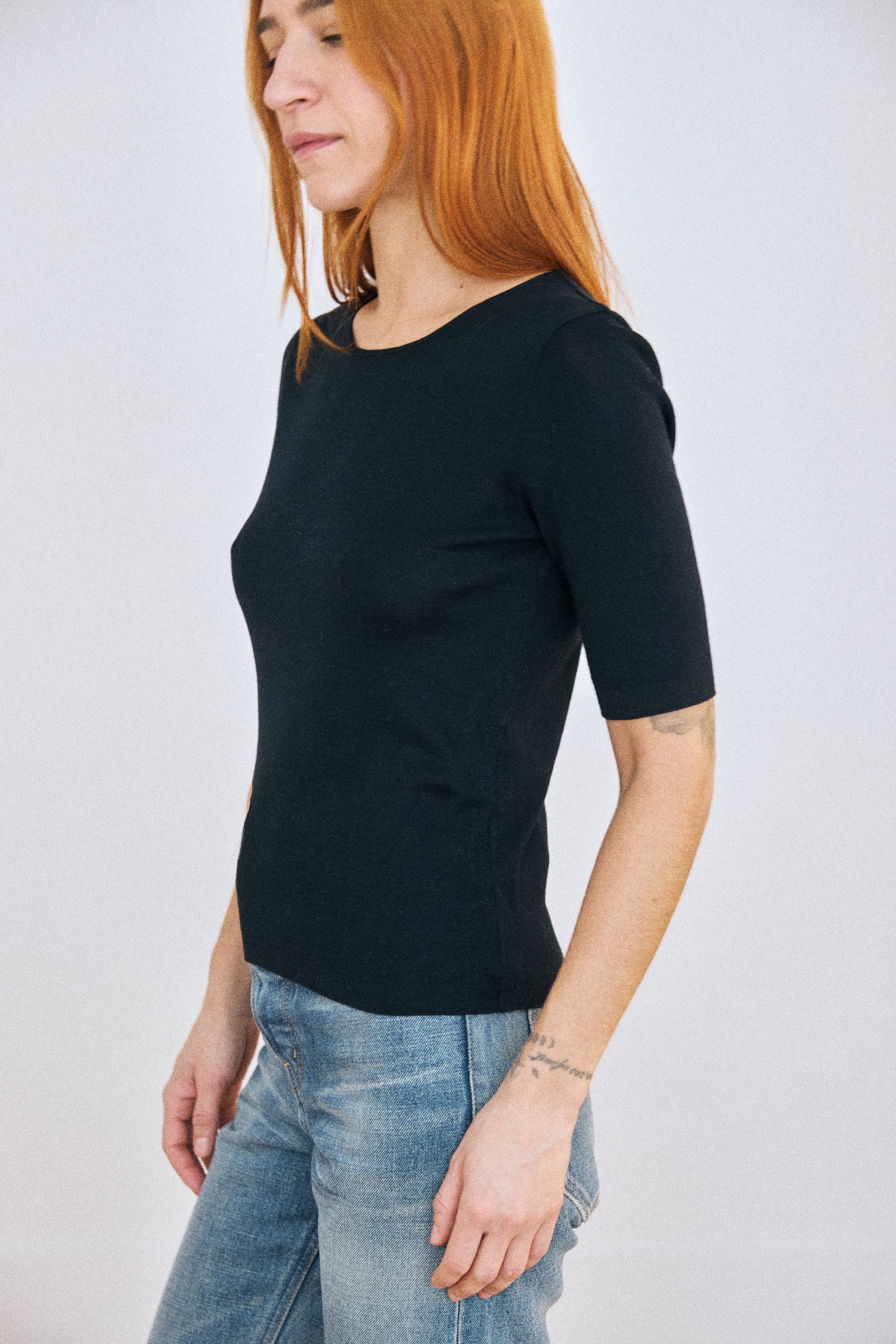 Woman wearing a black t-shirt and blue jeans against a white background