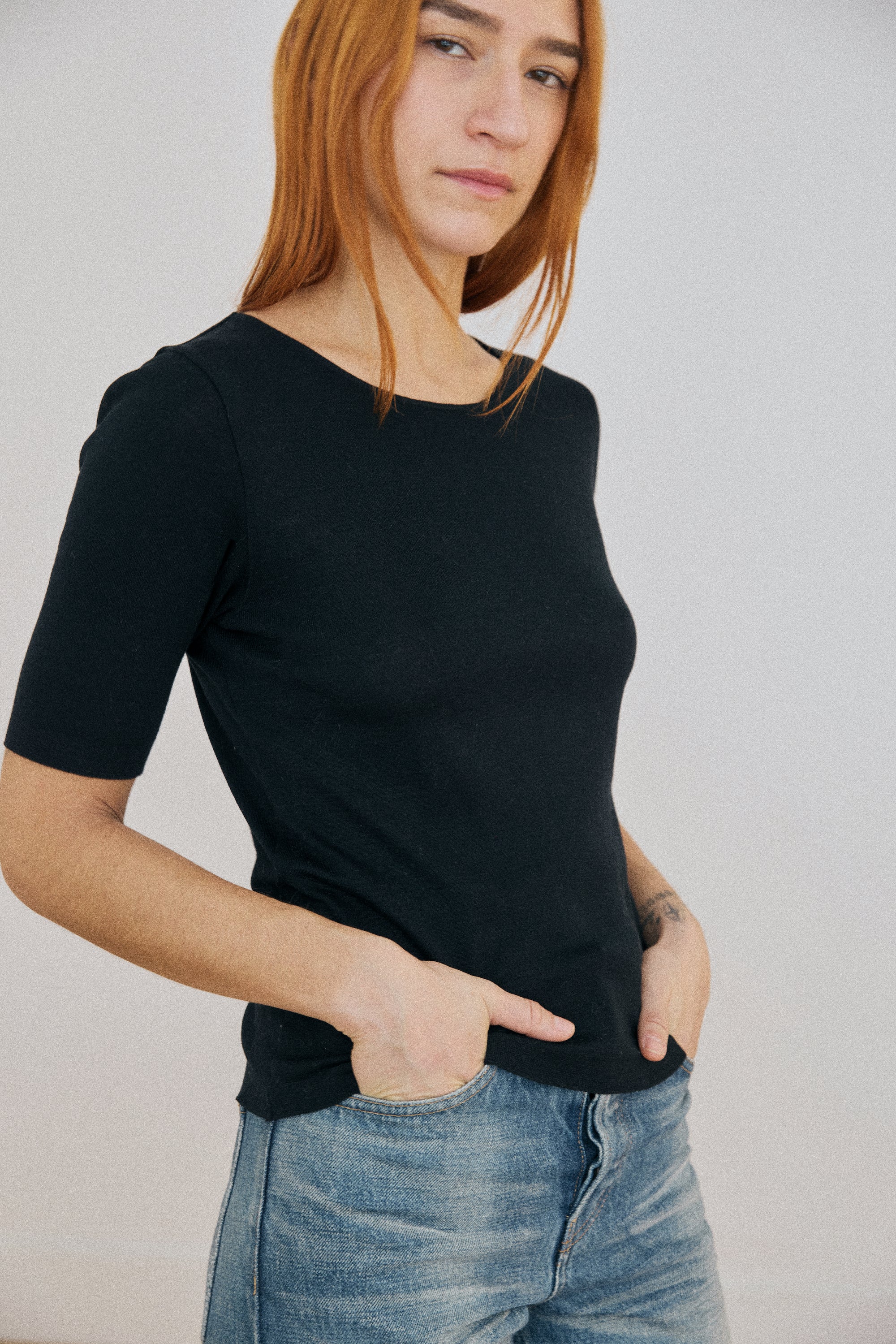 Person wearing a black t-shirt and blue jeans against a plain background