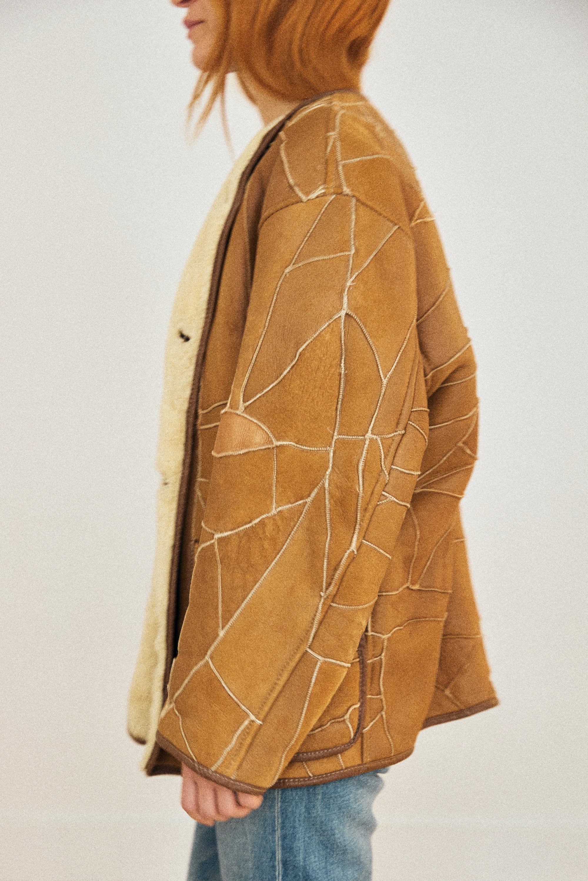 Person wearing a brown jacket with abstract white lines on a plain background