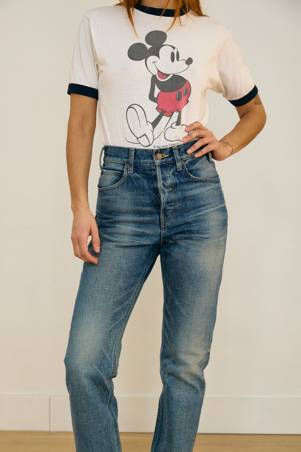 Person wearing a graphic t-shirt and blue jeans standing against a plain background
