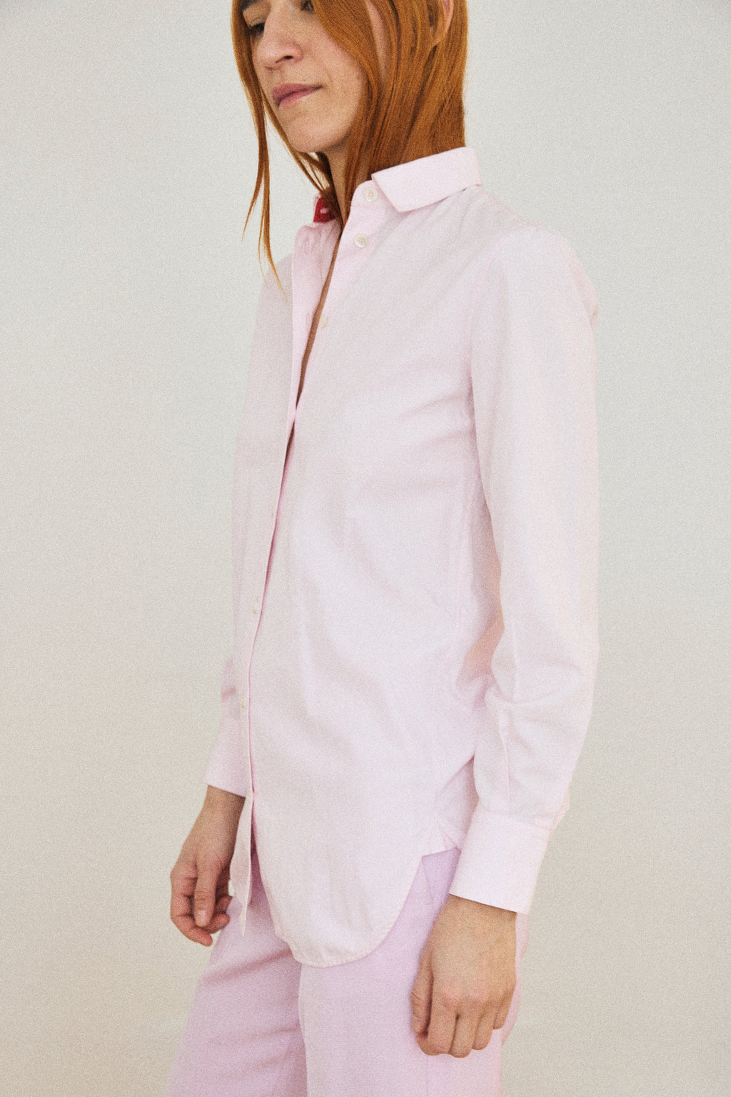 Person wearing a light pink shirt and pants against a plain background