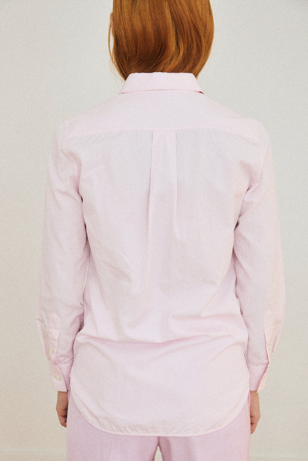 Person wearing a light pink shirt and pants on a plain background