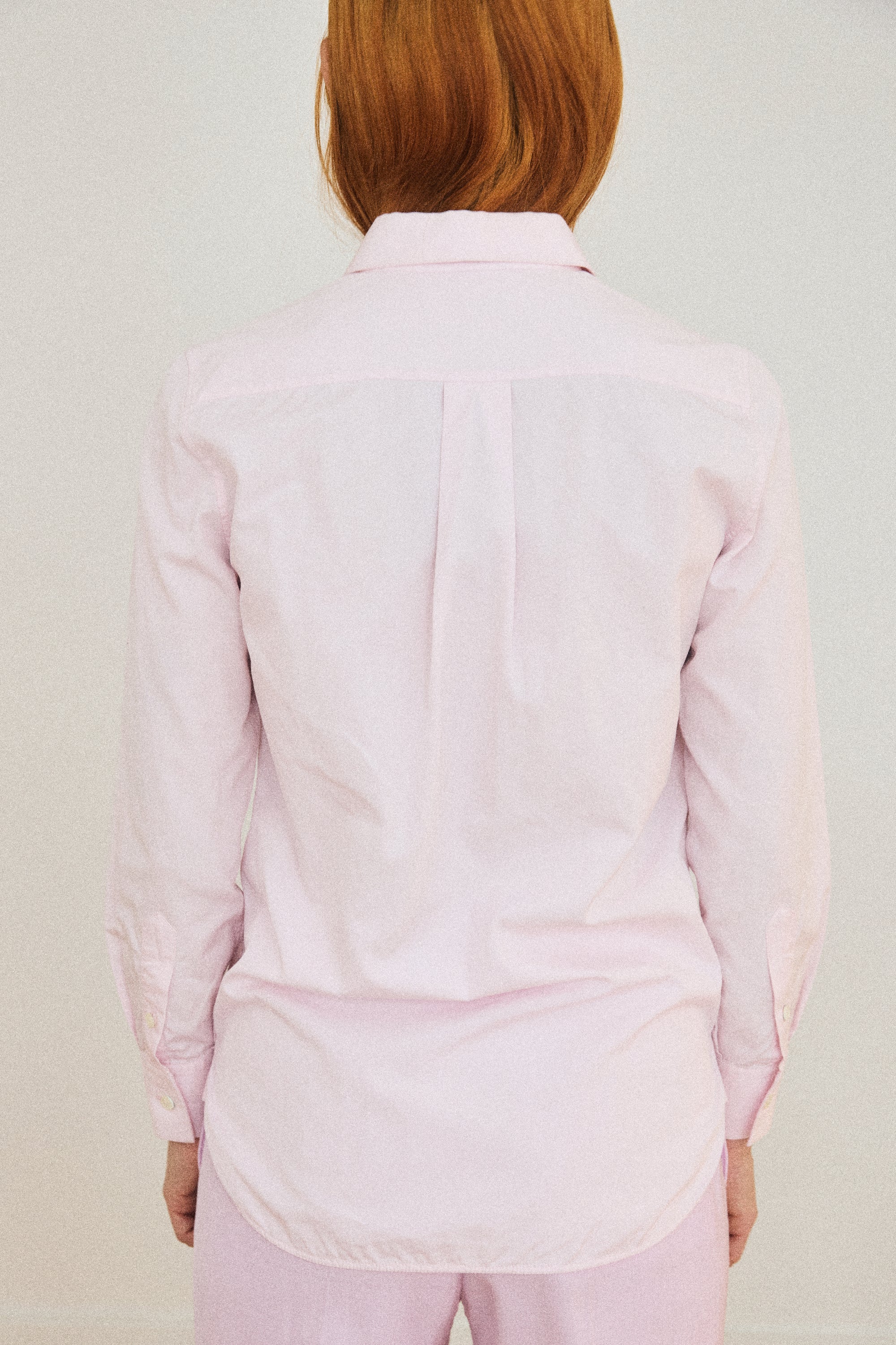 Person wearing a light pink shirt and pants on a plain background