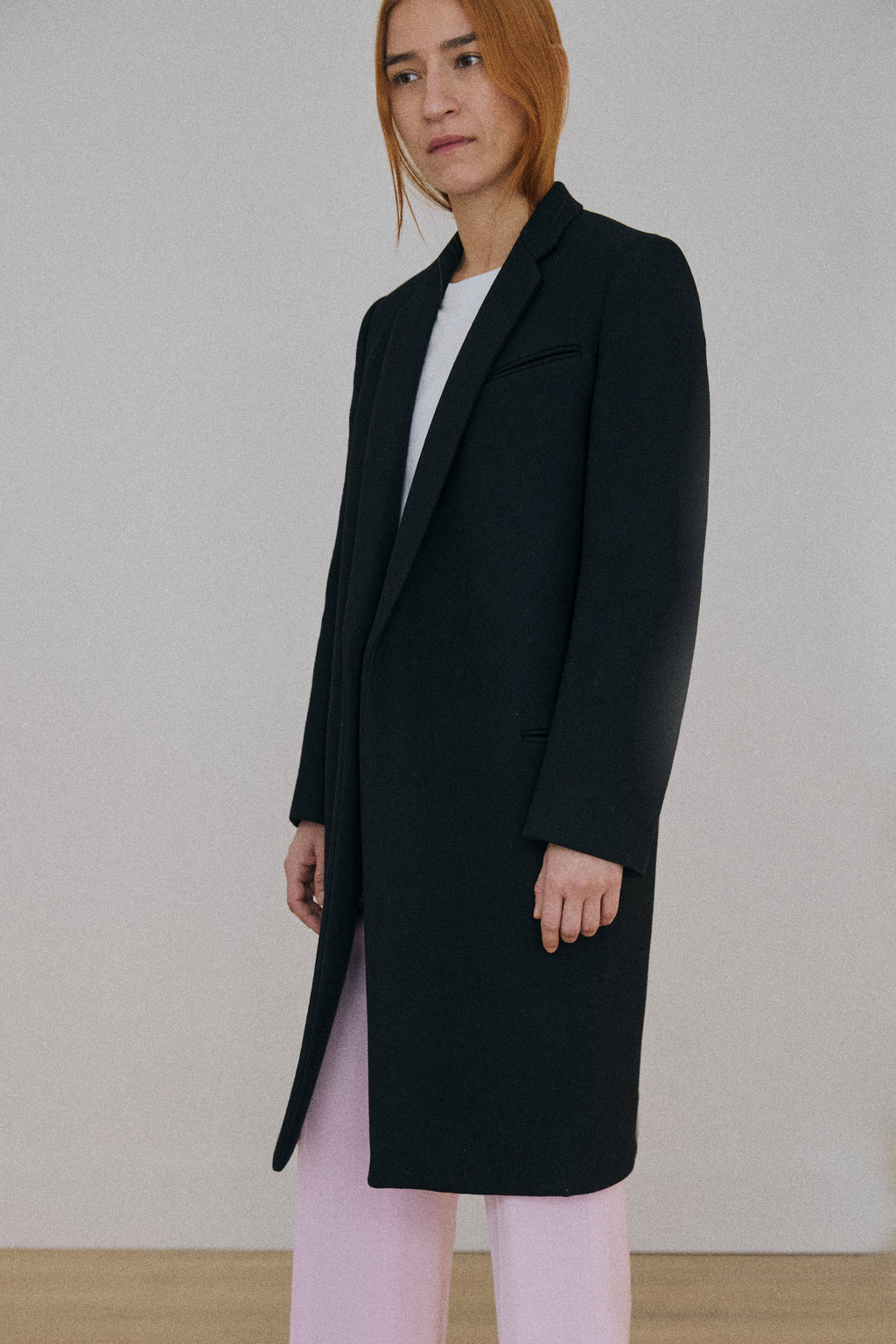 Person wearing a black coat with a plain background