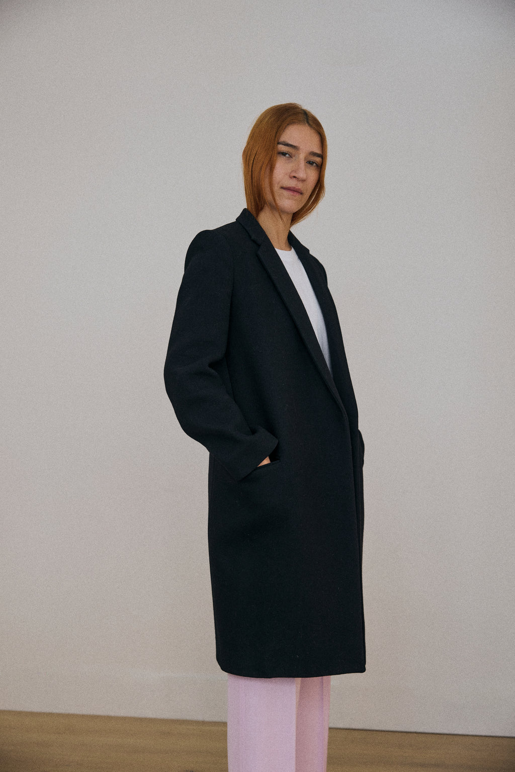 Person wearing a black coat against a plain background