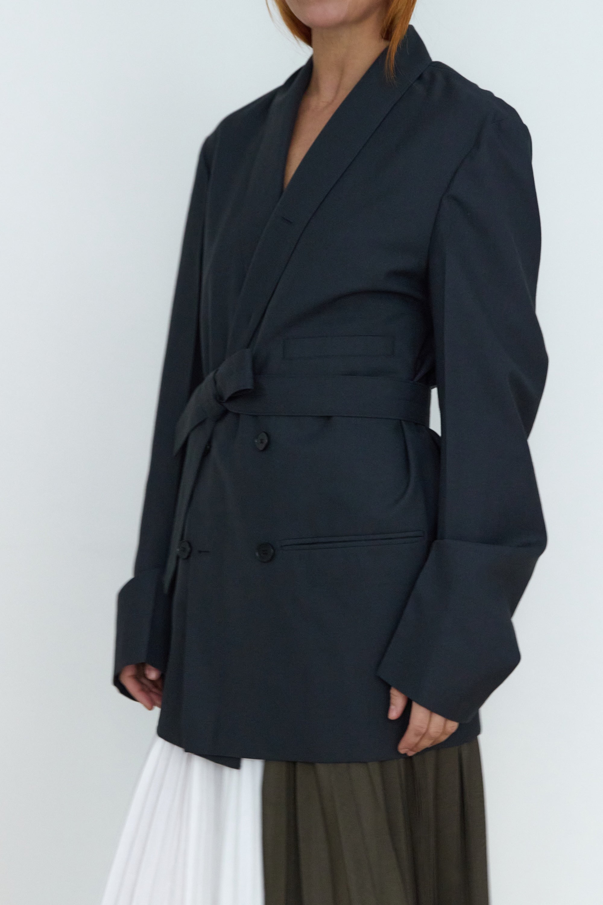 Person wearing a black blazer against a white background