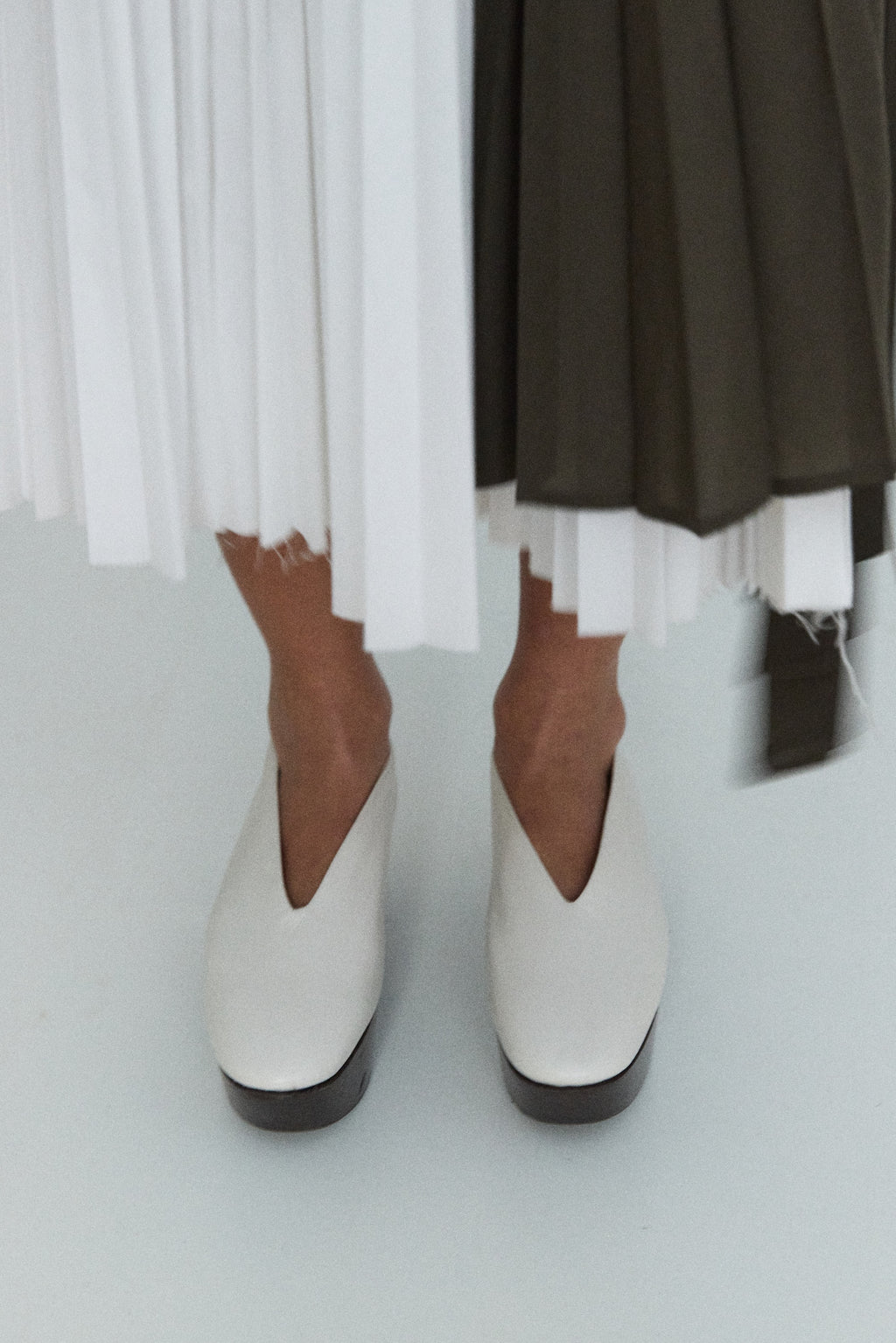 White ankle boots worn with a dark skirt and white socks on a light background