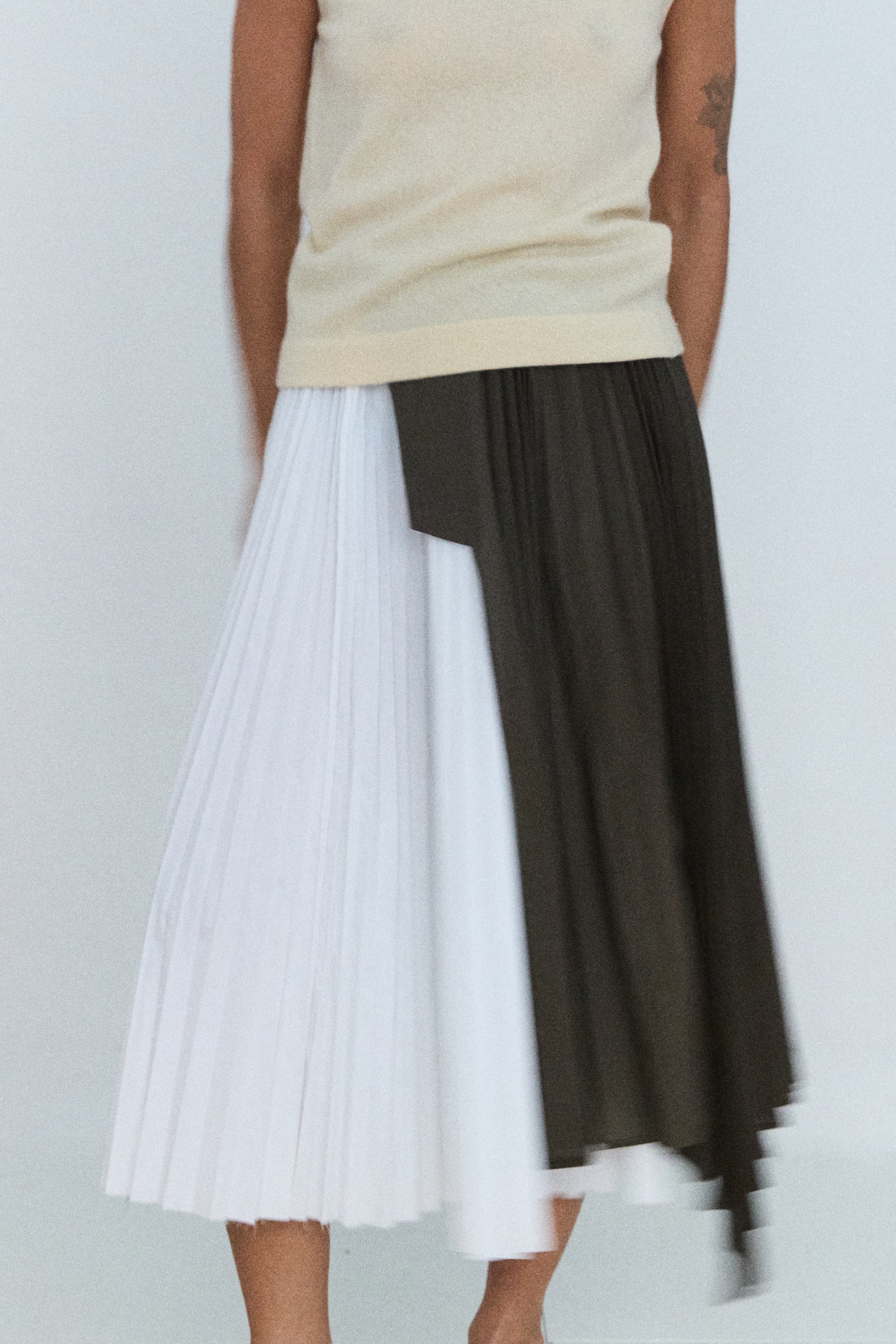 Person wearing a two-tone skirt with white and black layers on a plain background