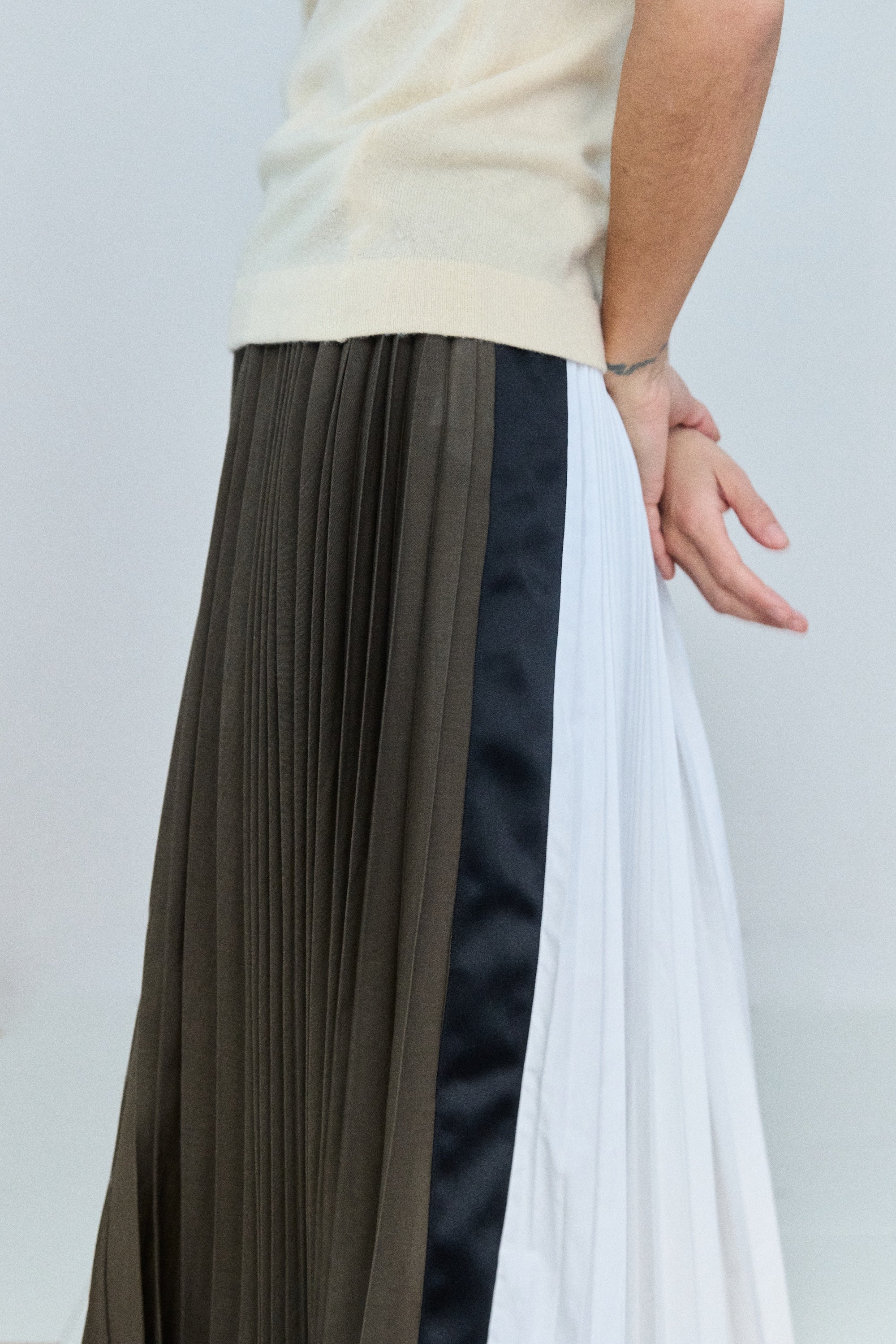 Person wearing a pleated skirt with a plain background