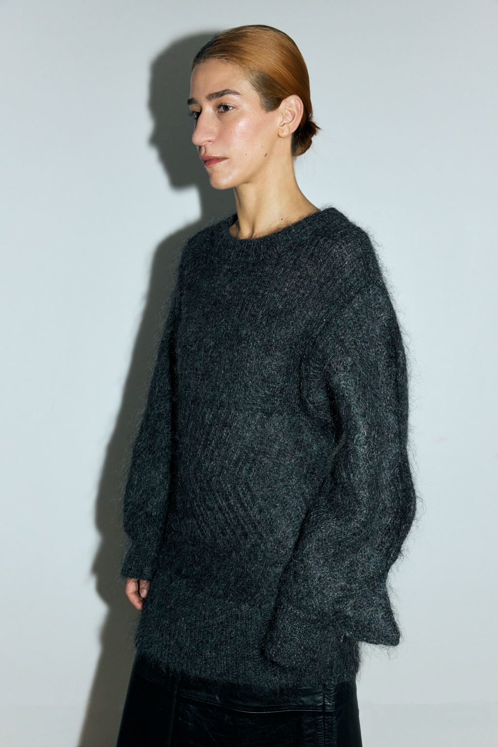 Person wearing a dark gray sweater against a plain background