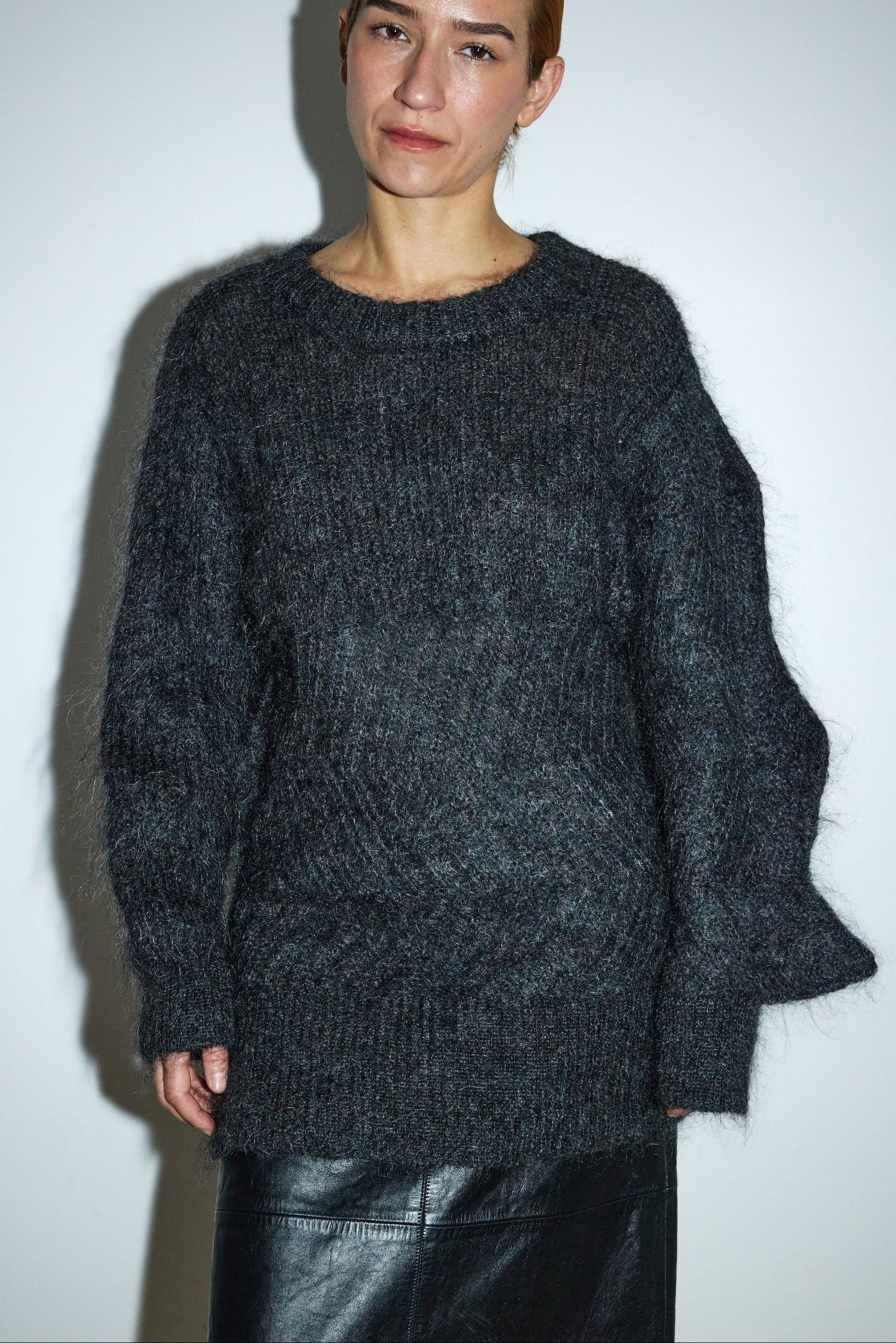 Person wearing a dark gray sweater against a white background