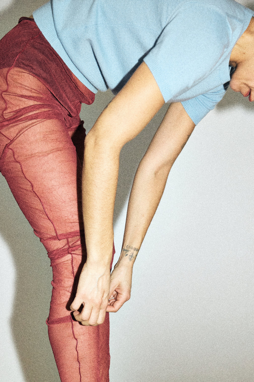 Person wearing red tights and a light blue top against a plain background