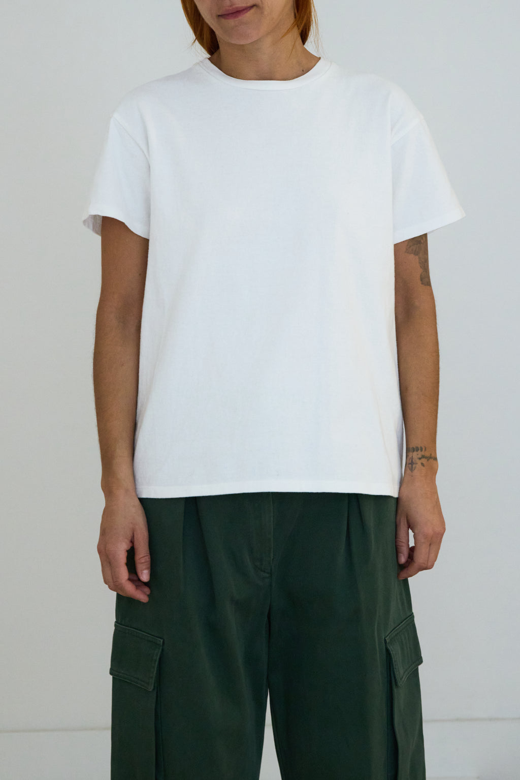 Person wearing a plain white t-shirt and green cargo pants against a white background