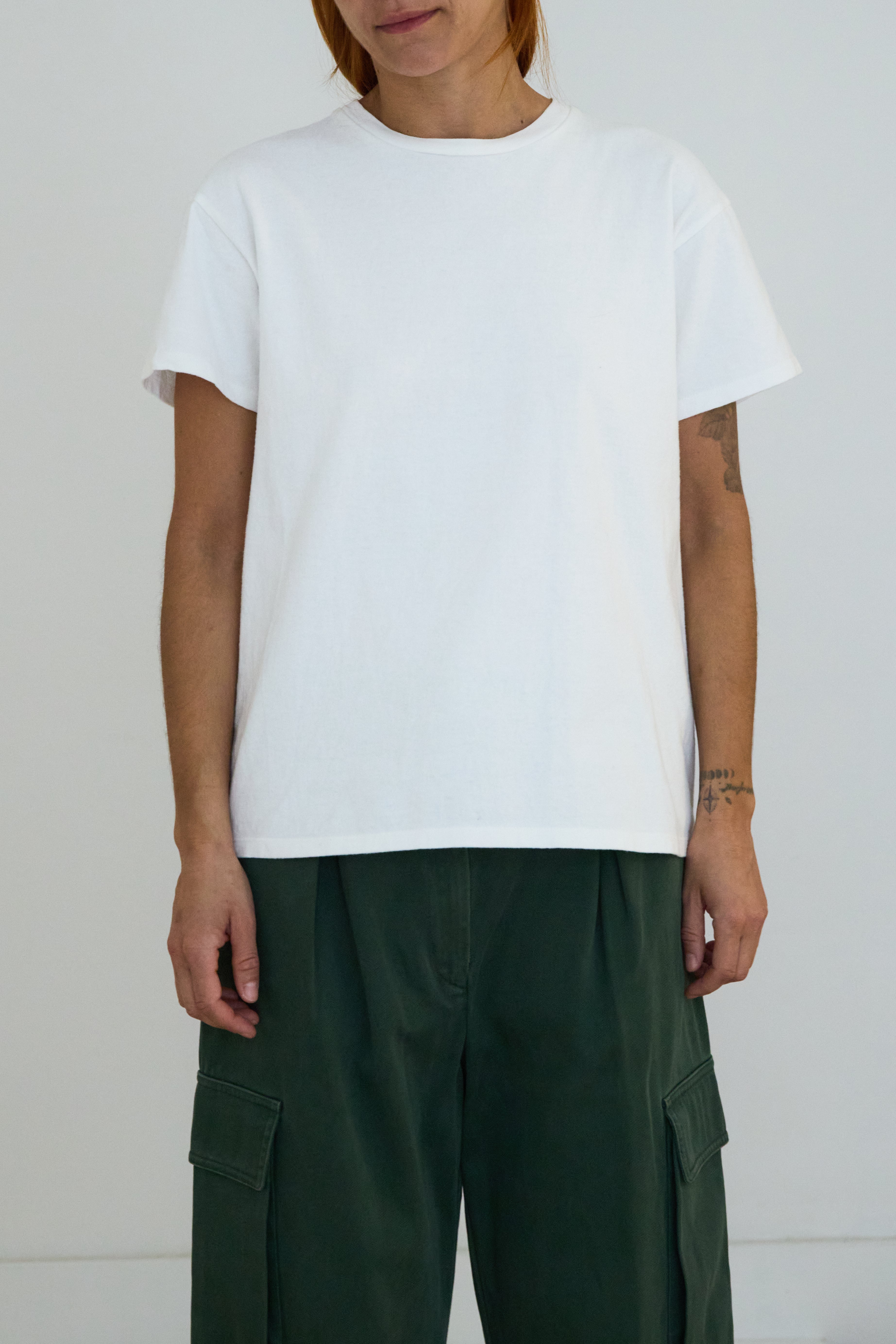 Person wearing a plain white t-shirt and green cargo pants against a white background