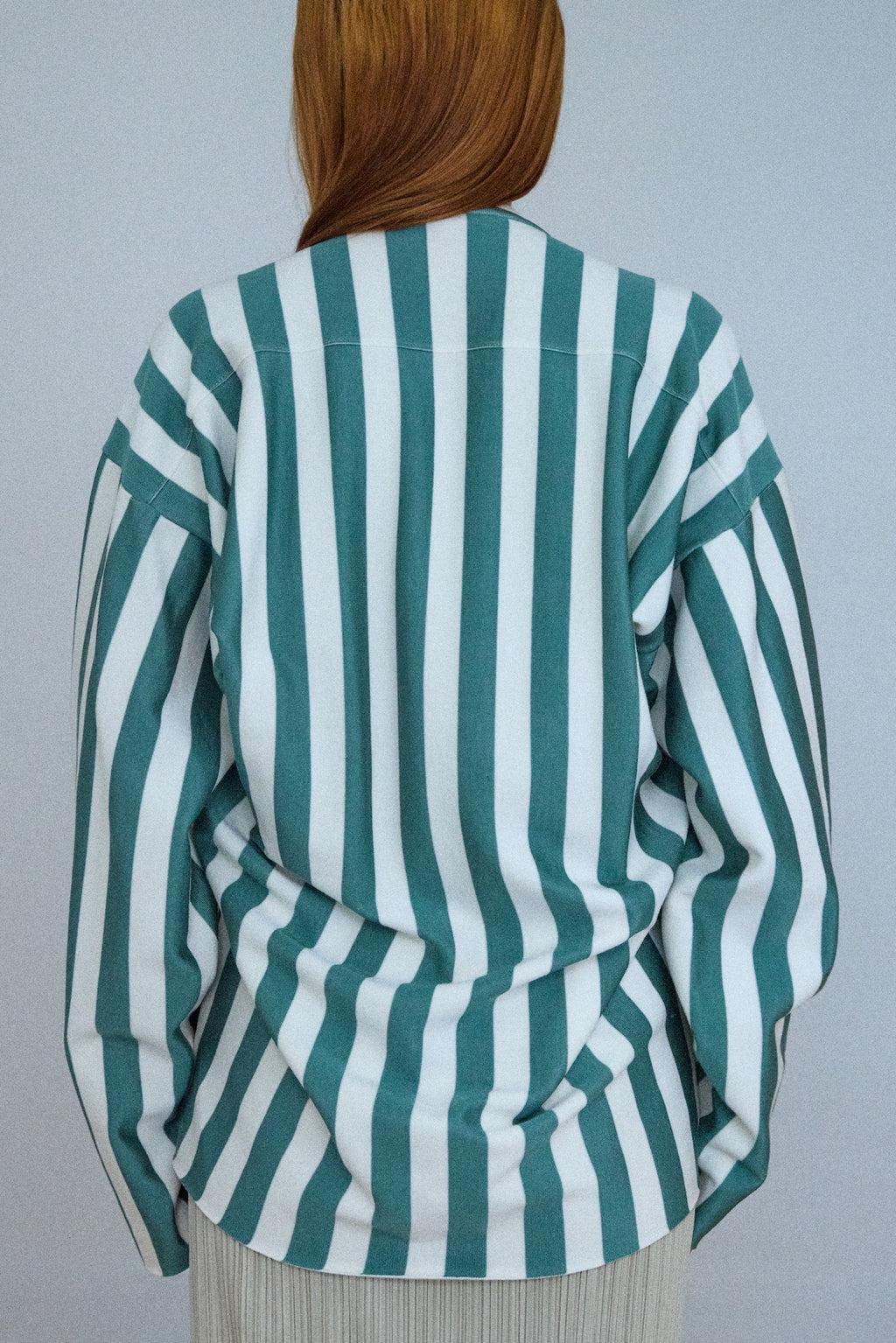Green and white striped shirt worn by a person against a plain background