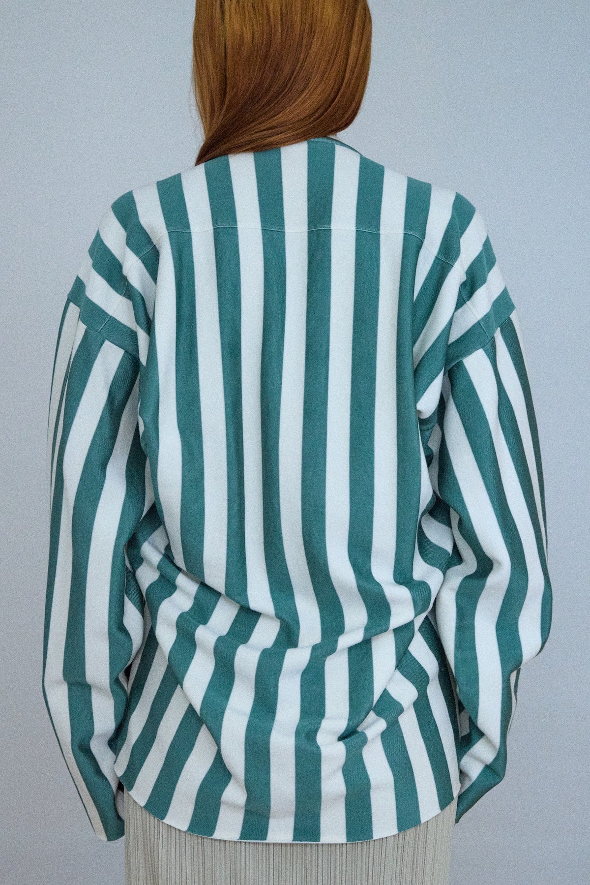 Green and white striped shirt worn by a person against a plain background