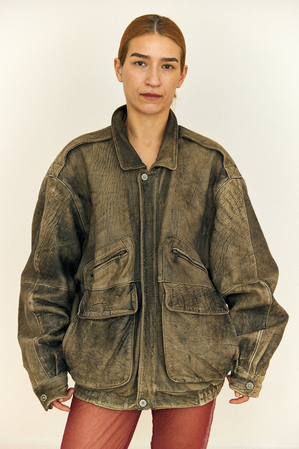 Person wearing a brown suede jacket on a plain background