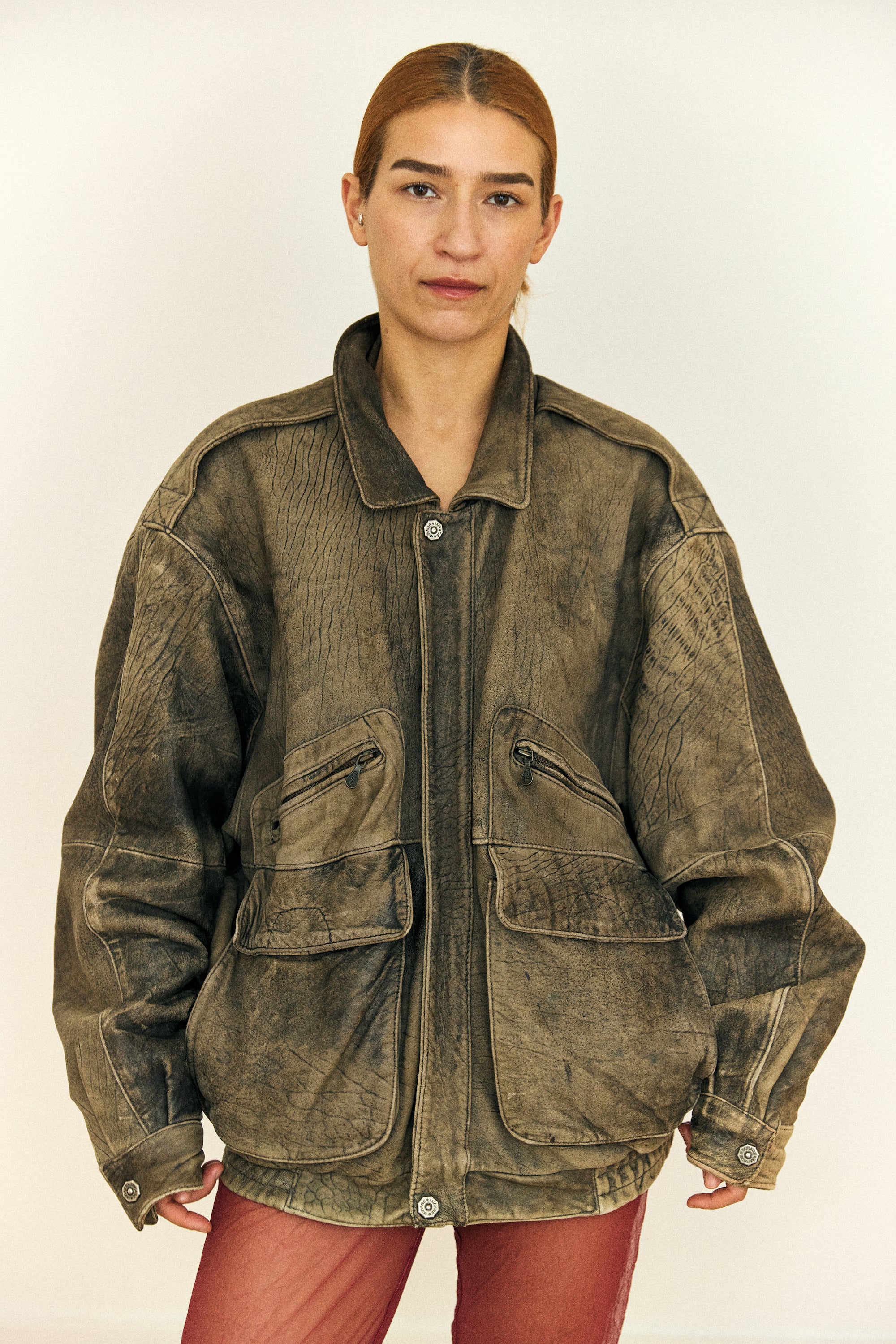 Person wearing a brown suede jacket on a plain background