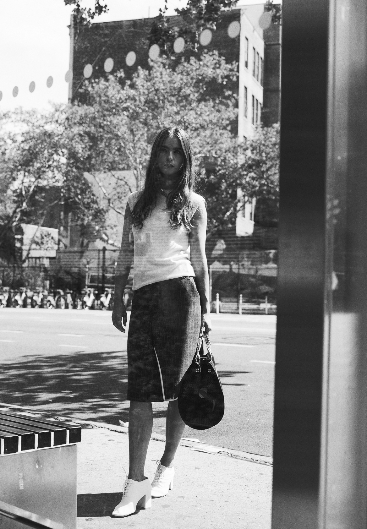 Black and white photo of a person holding a bag on a city street.