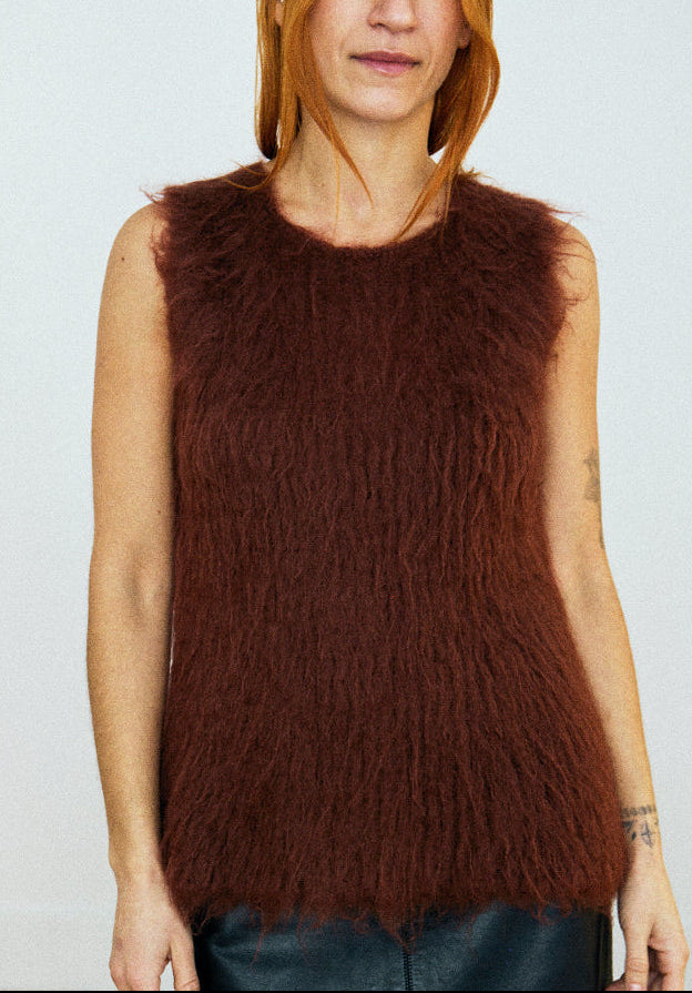 Woman wearing a brown sleeveless textured top against a plain background