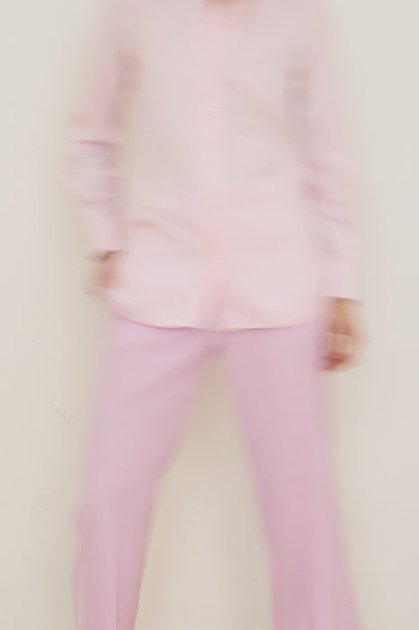 Person wearing a pink outfit with a blurred face on a white background